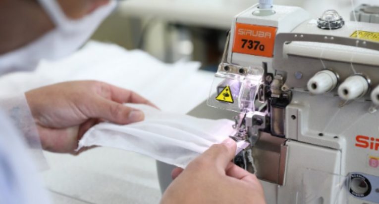 #pracegover Na imagem um profissional produz máscaras de proteção facial