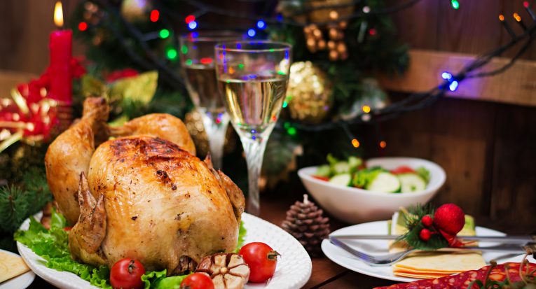 Baked turkey or chicken. The Christmas table is served with a turkey, decorated with bright tinsel and candles. Fried chicken, table. Christmas dinner.